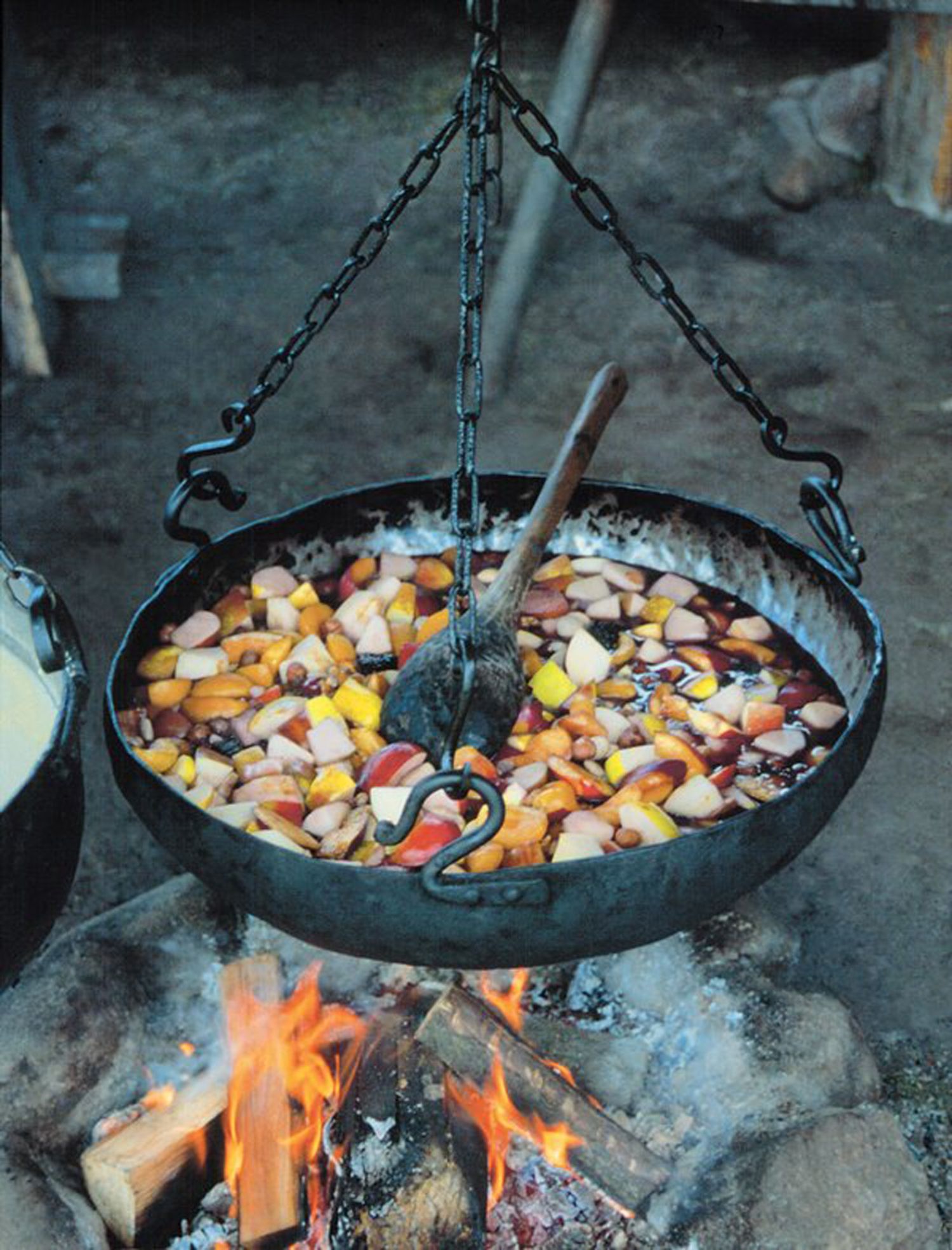 Über einem Lagerfeuer hängt ein eiserner Kessel. Darin kocht eine Suppe aus verschiedenfarbigen Früchten. Ein Holzlöffel zum Umrühren ist auf den Rand des Kessels gelegt. (© LAKD M-V/LA)