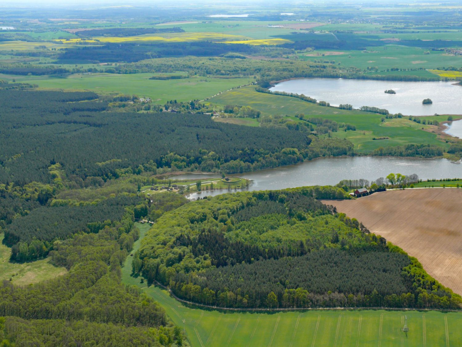 Aus der Vogelperspektive ist eine Landschaft mit viel Wald, Wiesen, Äckern und Seen zu erkennen. (© LAKD M-V/LA)