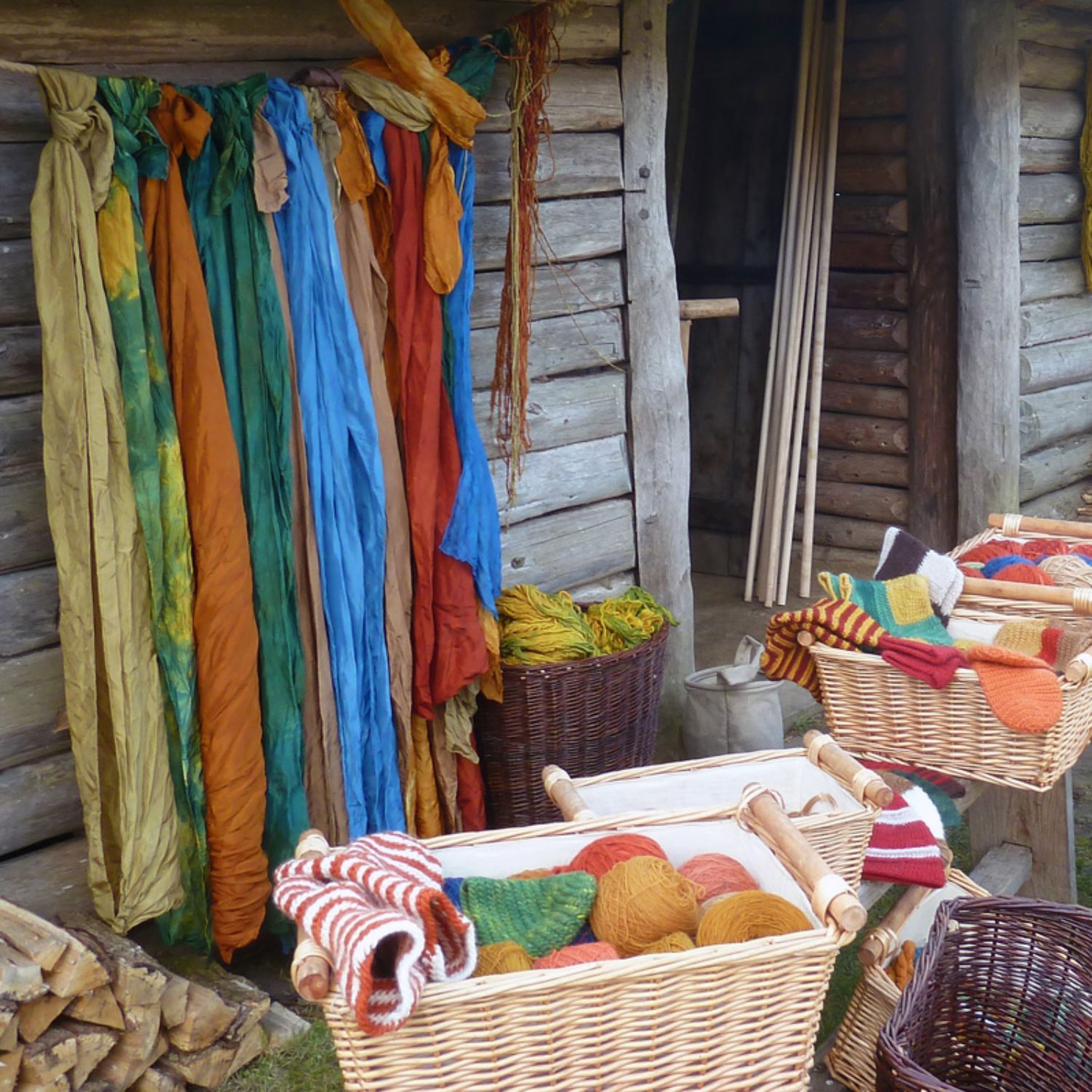 Farbenfroh in den Herbst! Foto: LAKD M-V/LA. Foto mit verschiedenfarbiger Wolle vor dem Eingang eines slawischen Hauses des Freilichtmuseums Foto: LAKD M-V/LA.