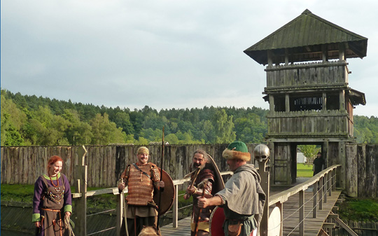 Mittelalterlich gekleidete Menschen begrüßen Ankommende vor dem Eingangstor. Foto: LAKD M-V/LA