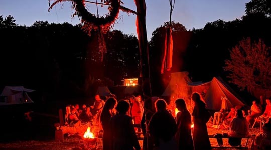 Tanzende Menschen um ein nächtliches Feuer